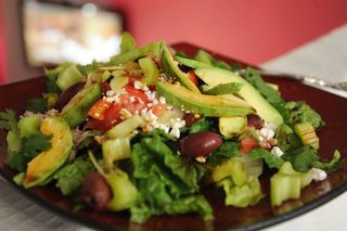 Perfectly delightful summer salad, avocado, celery, romaine lettuce, olives, feta cheese, almonds, tomato, tamari sauce, olive oil, served on a square maroon zen plate, silver fork, second floor loft, Seattle, Washington, USA